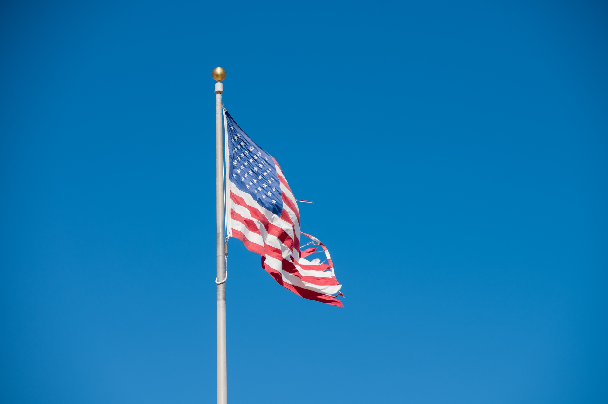 Tattered looking american flag on pole